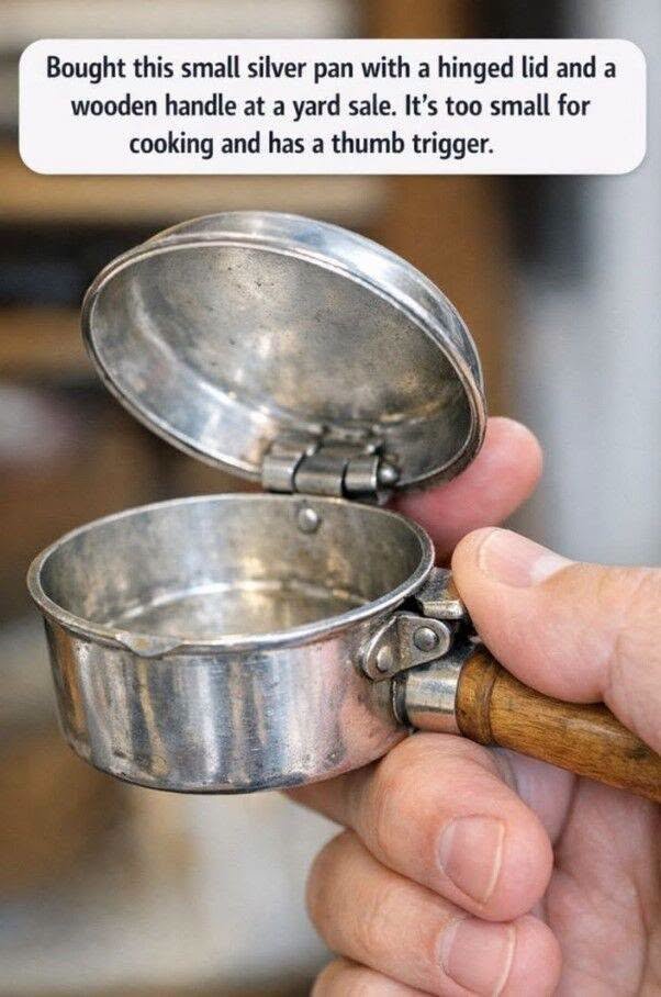Bought this small silver pan with a hinged lid and a wooden handle at a yard sale. It’s too small for cooking and has a thumb trigger.